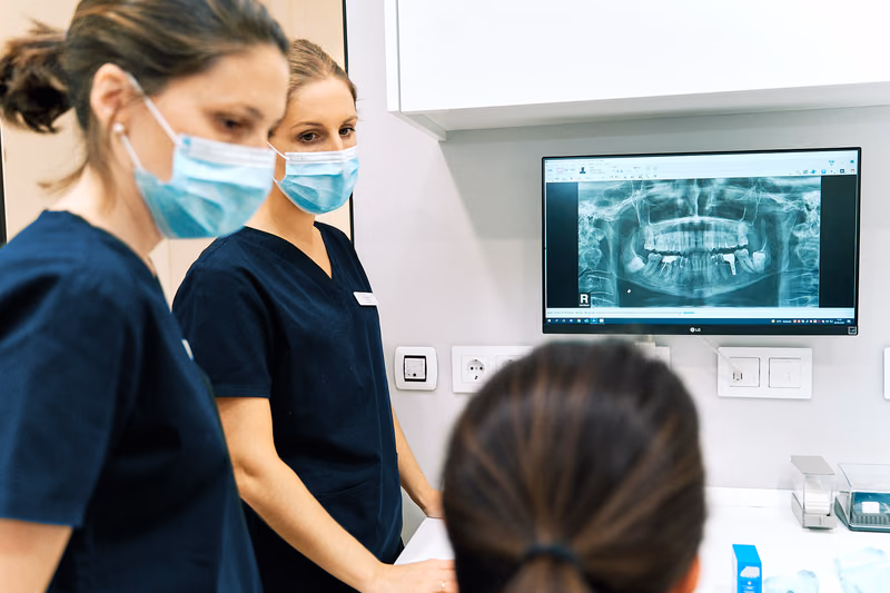 El equipo junto a una paciente durante una valoración, con una radiografía dental en el monitor